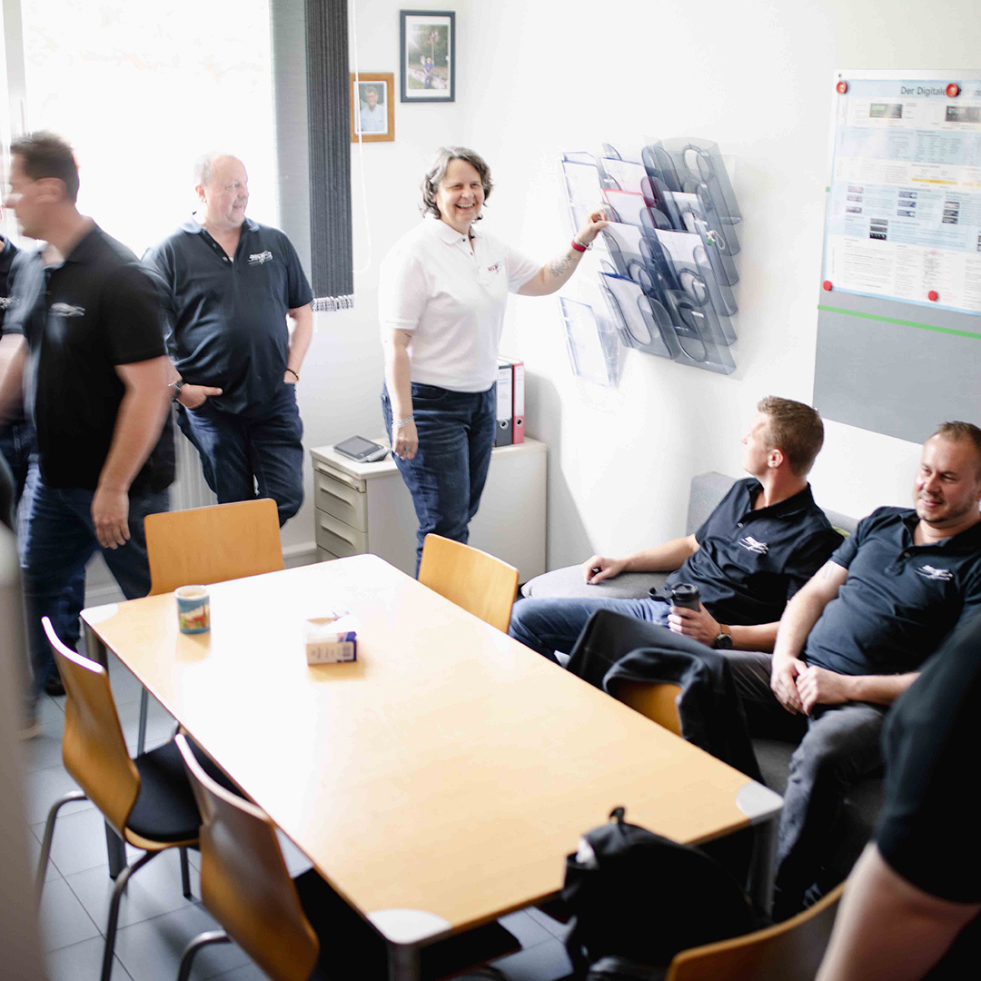 Bus-Team sitzen und stehen in einem Aufenthaltsraum.